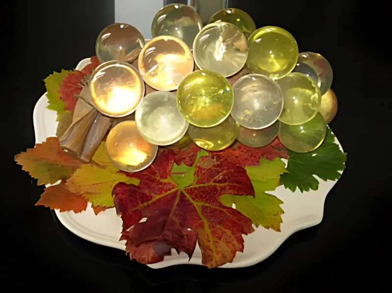 Wine glasses arranged with colorful autumn grape leaves on white plate