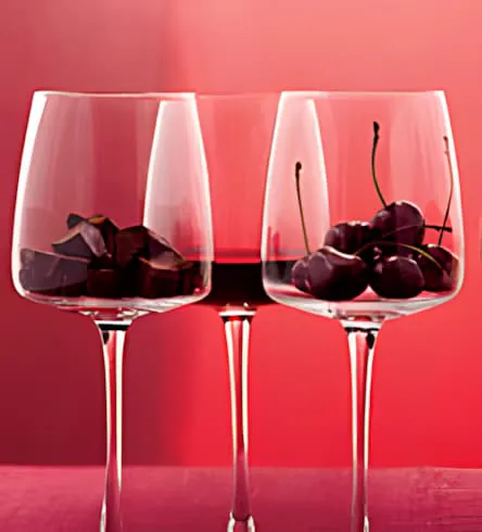Three wine glasses with dark cherries showcasing Cabernet Sauvignon characteristics